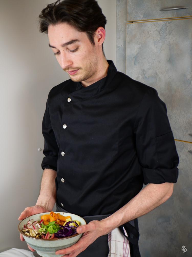 Hugo Picard en veste noire, présentant un bol de légumes